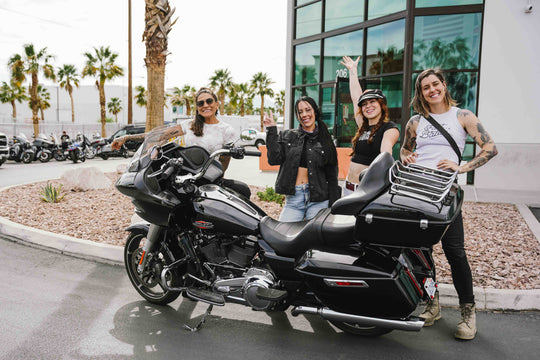 Female riders making peace signs around a black Harley-Davidson touring motorcycle in a parking lot blog cover