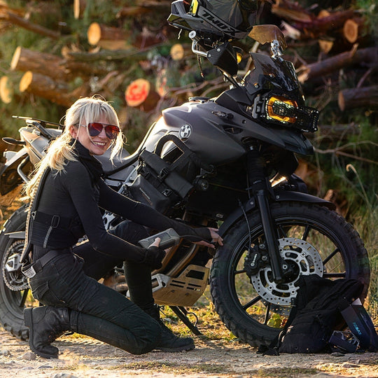Female motorcyclist kneeling to use an ASMAX air pump on her BMW GS motorcycle blog cover