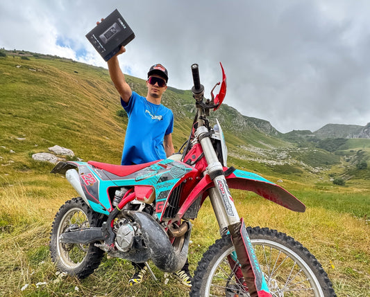 Rider standing in a grassy mountain field holding an ASMAX air pump product box blog cover