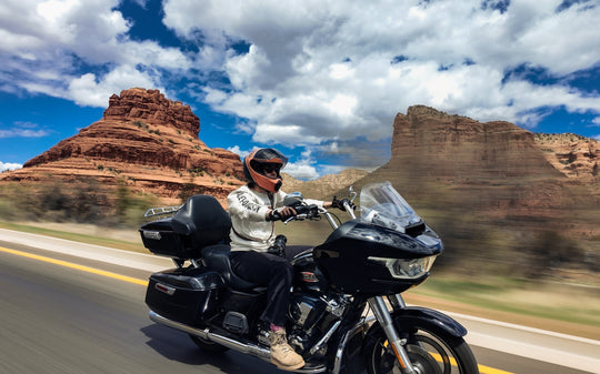  Touring motorcyclist cruising through a red rock canyon on a black cruiser, blog cover.